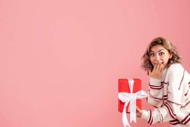 Free photo young female holding present on pink