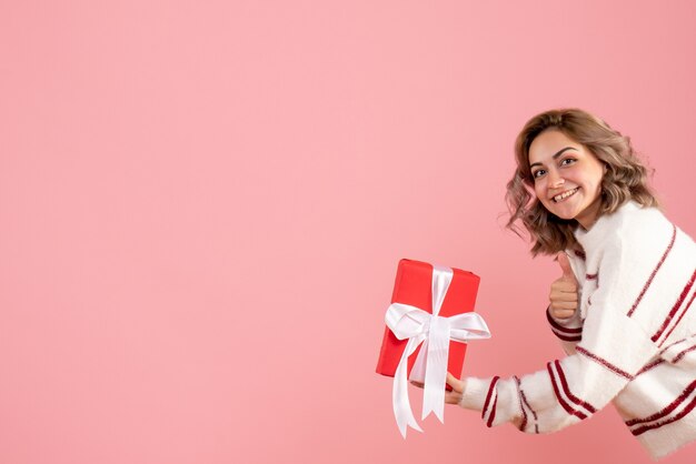 young female holding present on pink