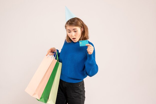 young female holding shopping packages and bank card on white