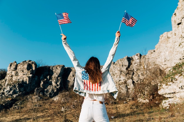 頭の上にアメリカの国旗を保持している若い女性