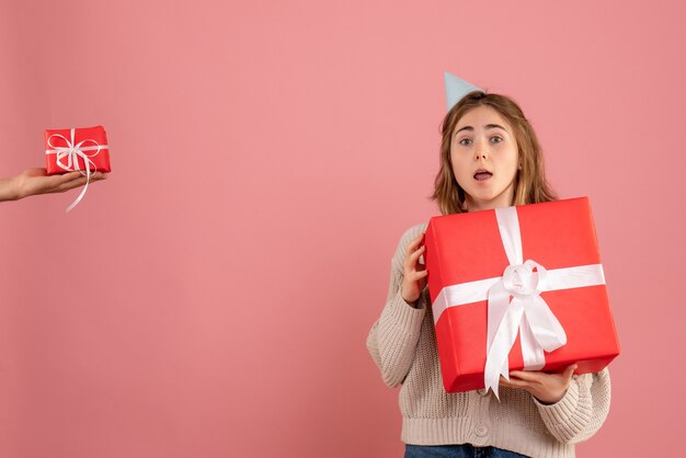 young female holding xmas present and accepting gift from male on pink