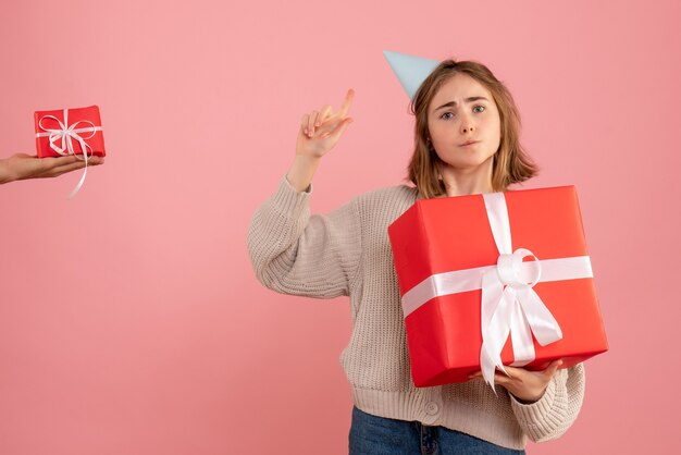 young female holding xmas present and accepting gift from male on pink