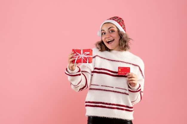 young female holding xmas present and bank card on pink