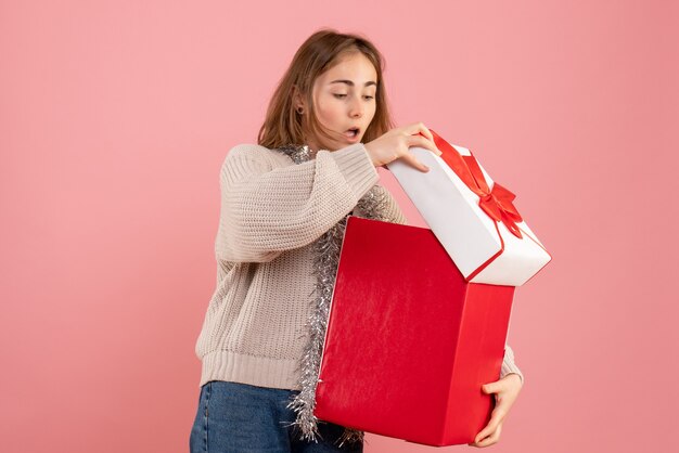 young female holding xmas present box on pink