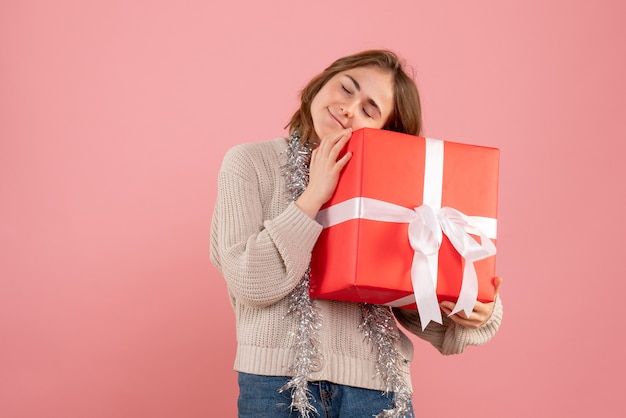 young female holding xmas present in her hands on pink