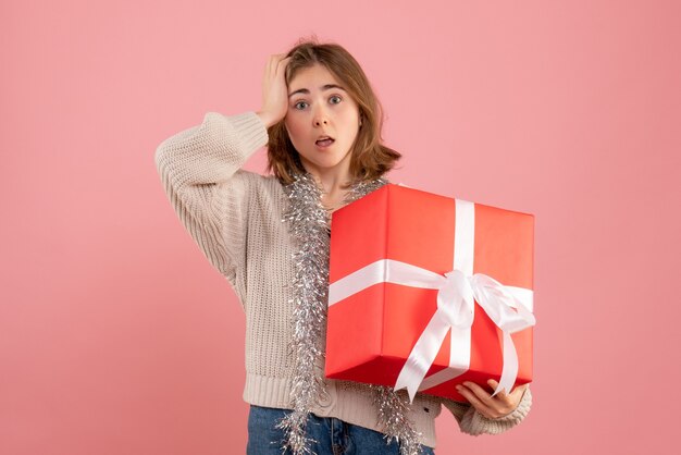 ピンクの彼女の手に存在するクリスマスを保持している若い女性