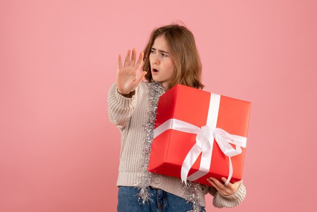 young female holding xmas present in her hands on pink