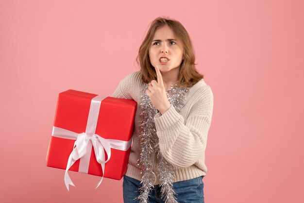 ピンクの彼女の手に存在するクリスマスを保持している若い女性