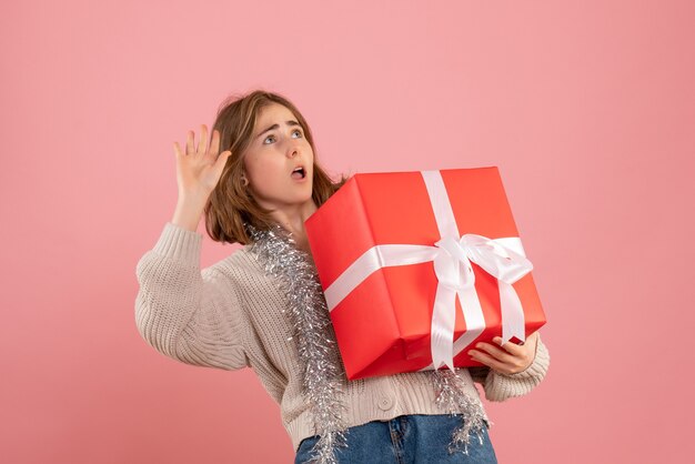 ピンクの彼女の手に存在するクリスマスを保持している若い女性