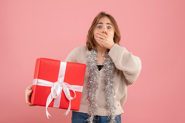 young female holding xmas present in her hands on pink