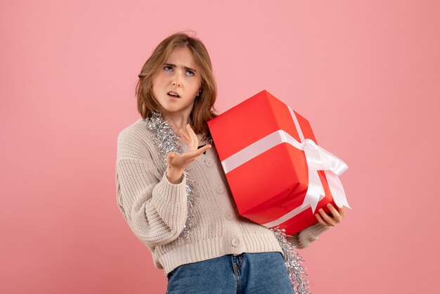 young female holding xmas present in her hands on pink