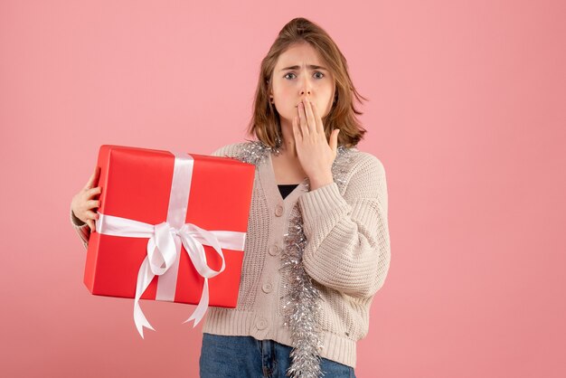 young female holding xmas present in her hands on pink