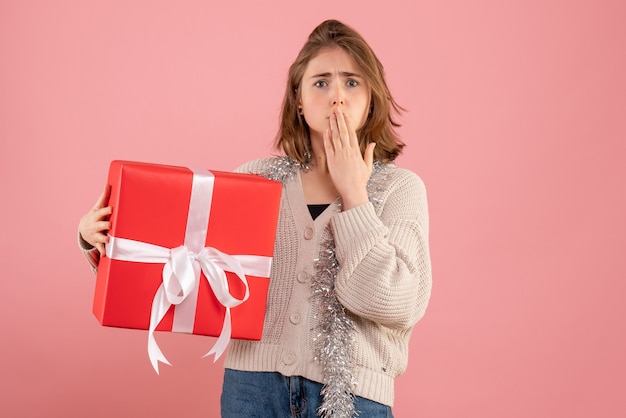 young female holding xmas present in her hands on pink