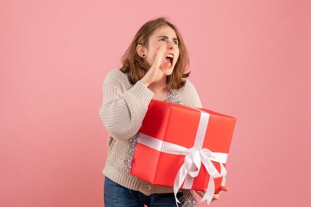 ピンクの彼女の手に存在するクリスマスを保持している若い女性