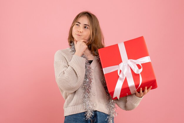 ピンクの彼女の手に存在するクリスマスを保持している若い女性