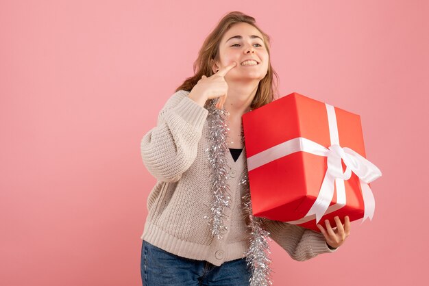 young female holding xmas present in her hands on pink