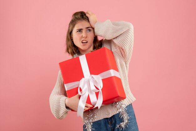 ピンクの彼女の手に存在するクリスマスを保持している若い女性