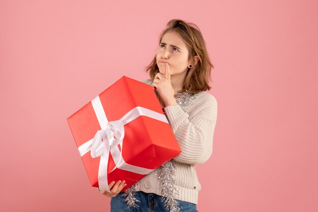 ピンクの彼女の手に存在するクリスマスを保持している若い女性