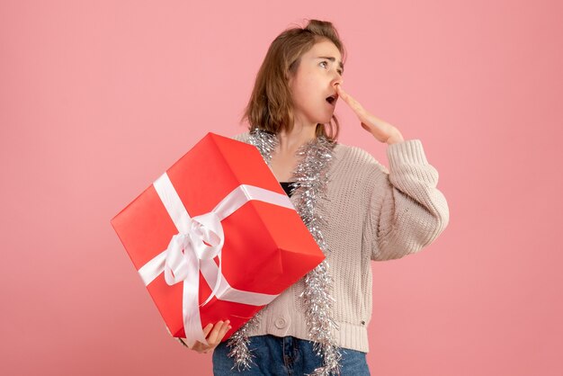 young female holding xmas present in her hands on pink