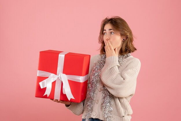 young female holding xmas present on pink