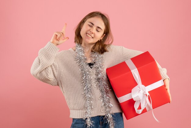 young female holding xmas present on pink