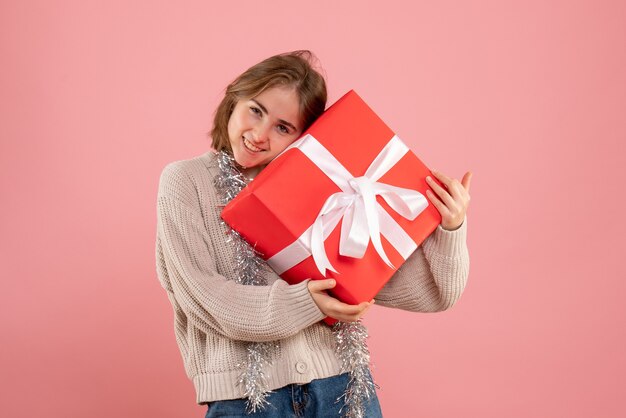 young female holding xmas present on pink