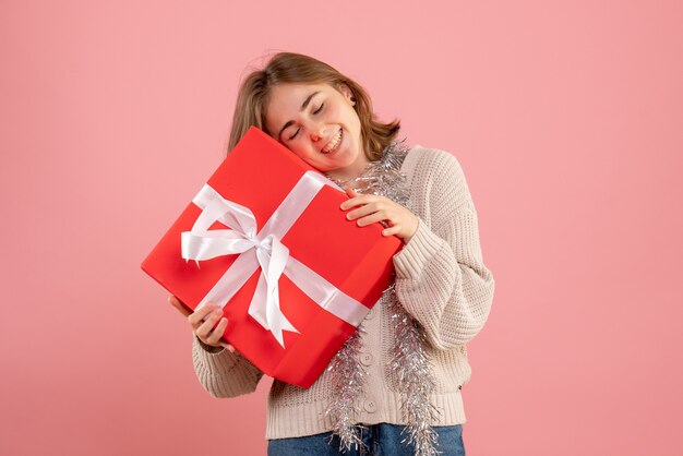 young female holding xmas present on pink