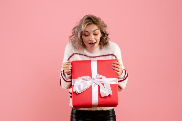 young female holding xmas present on pink