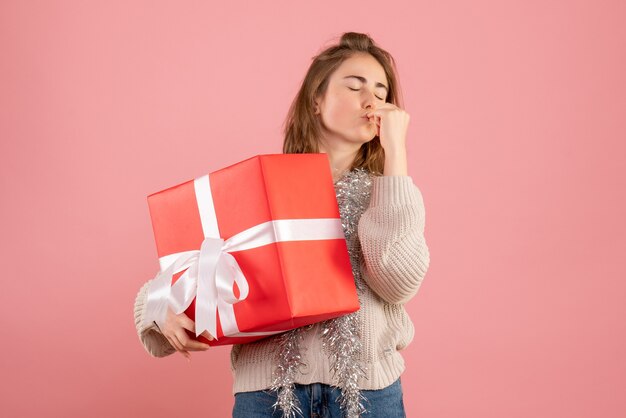 ピンクにクリスマスプレゼントを保持している若い女性