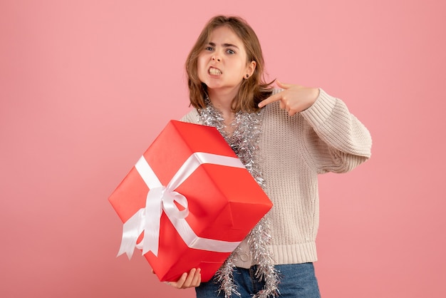 ピンクにクリスマスプレゼントを保持している若い女性