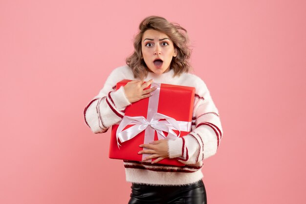 young female holding xmas present on pink