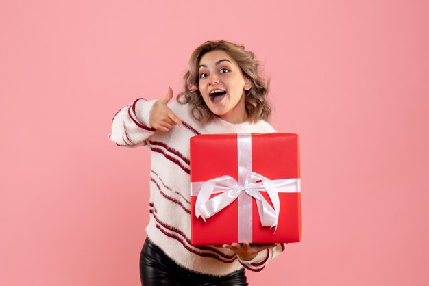 young female holding xmas present on pink