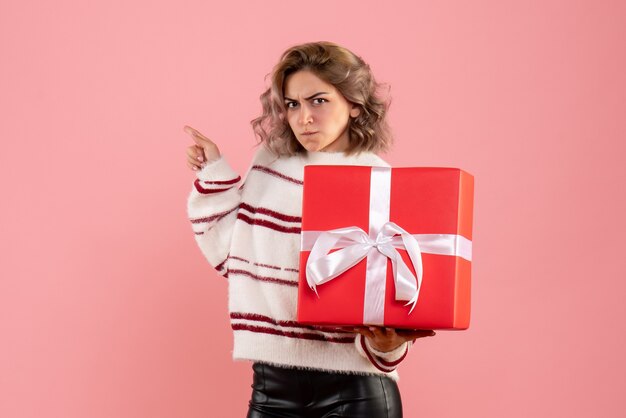 young female holding xmas present on pink