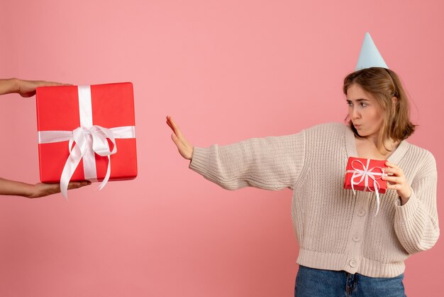 young female holding xmas present and rejecting gift from male on pink
