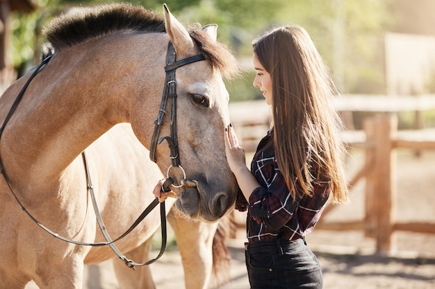Young female horse farm manager caring and petting young stallion Dream career taking care about animals