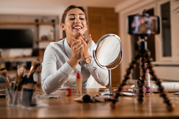 Young female influencer applying face powder while vlogging at home