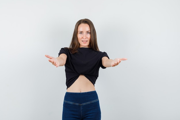 Young female inviting to come in black blouse, pants and looking kind