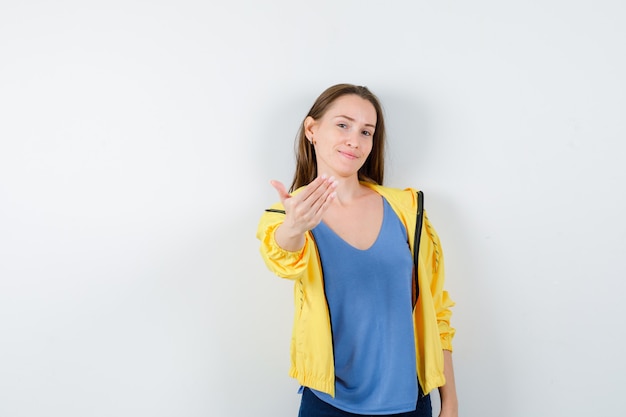 Young female inviting to come in t-shirt, jacket and looking confident. front view.