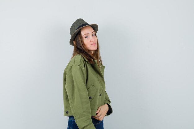 Young female in jacket, pants, hat and looking elegant. .