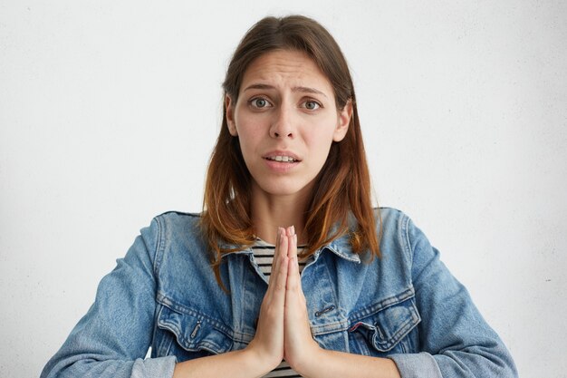 young female in jeans jacket asking for forgiveness