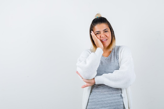 Free photo young female keeping palm on cheek in t-shirt, cardigan and looking merry , front view.