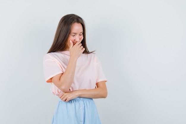 Young female laughing with hand over mouth in t-shirt, skirt , front view.