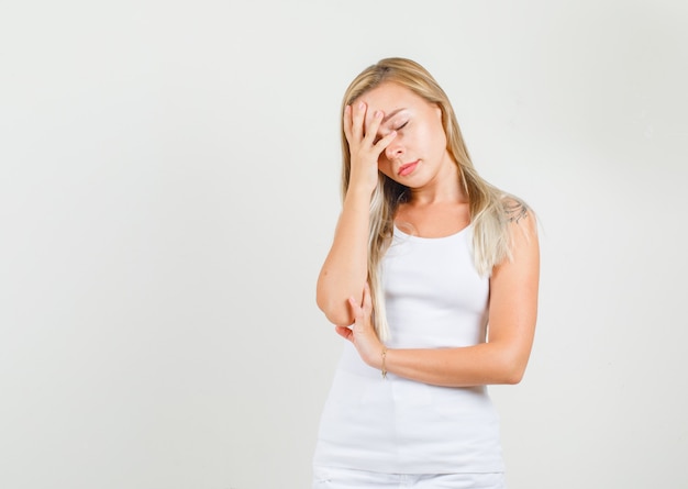 Free photo young female leaning face on hand in singlet and looking tired.