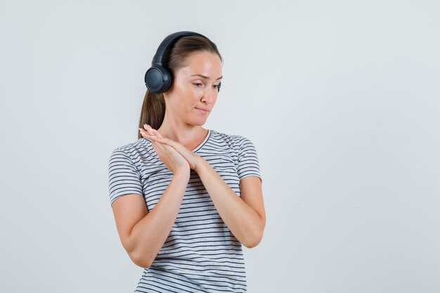 Young female listening carefully with headphones in striped t-shirt , front view.