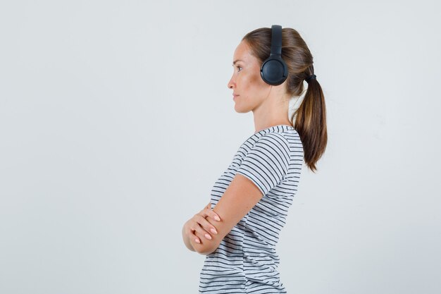 Free photo young female listening carefully with headphones in striped t-shirt .