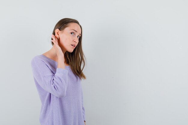 Young female listening in lilac blouse and looking attentive 