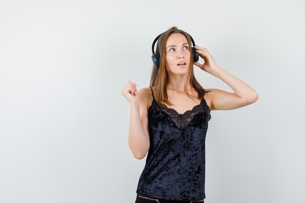 Молодая женщина слушает музыку в наушниках в черной майке