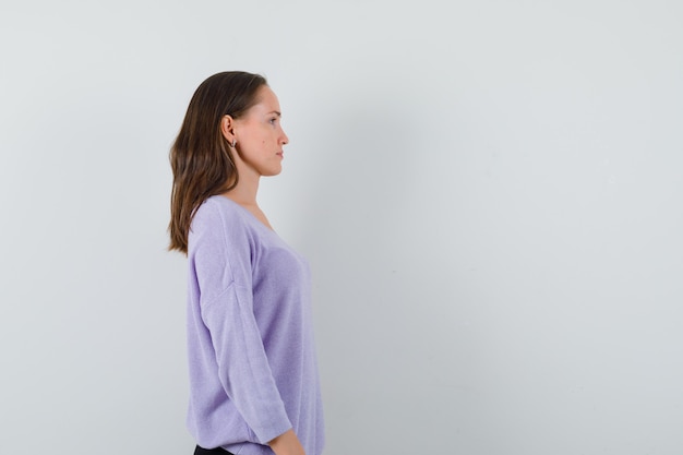 Young female looking aside in lilac blouse and looking calm . space for text