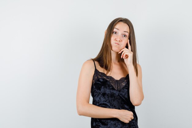 Young female looking away in black singlet and looking hesitant.