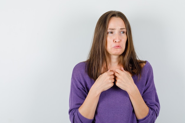 Young female looking away in violet shirt and looking offended. front view.